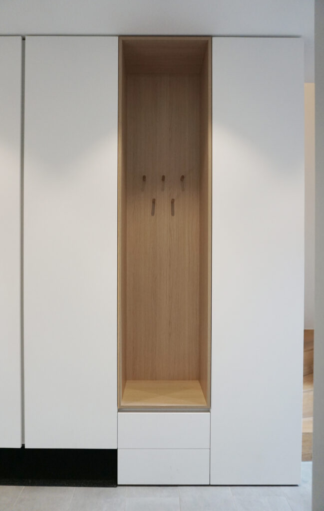 Weißer Garderobenschrank mit offener Nische in Holz und Wandhaken