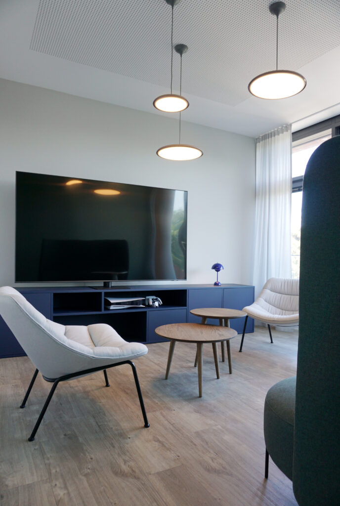 Loungebereich mit Sesseln, blauem Sideboard und Pendelleuchten