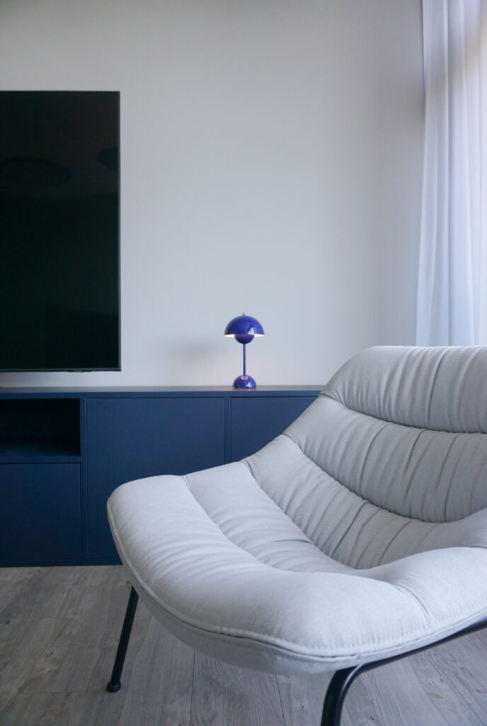 Detail blaues Sideboard mit Tischleuchte und grauem Sessel